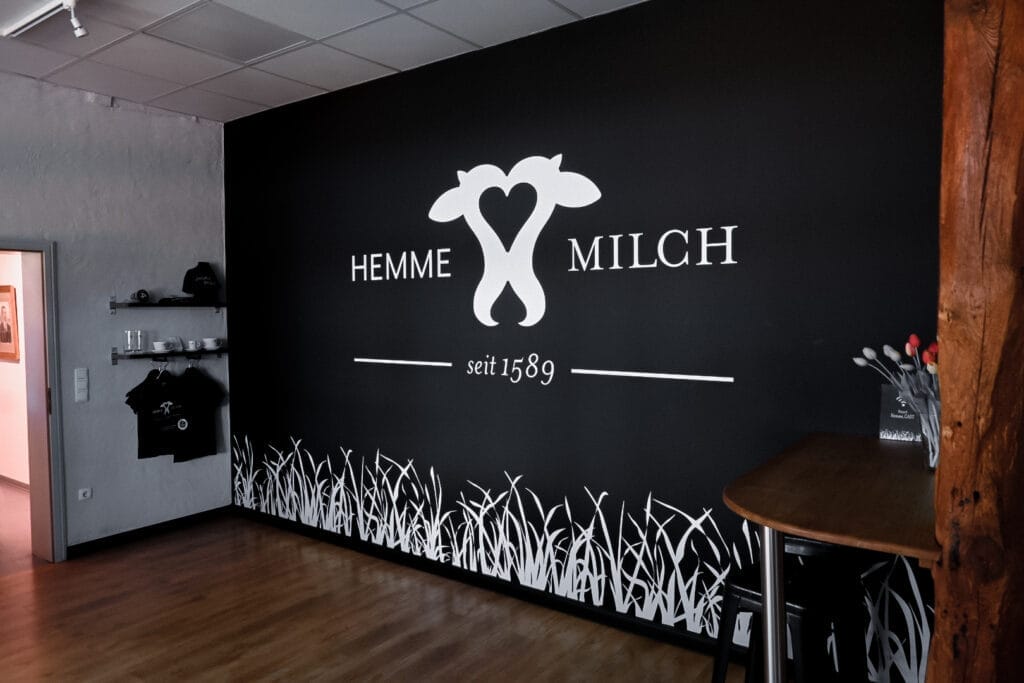 Hemme Milch Logo an der Wand des traditionellen Hofladens - regionale Partnerschaft seit 1589 mit #daskollektiv